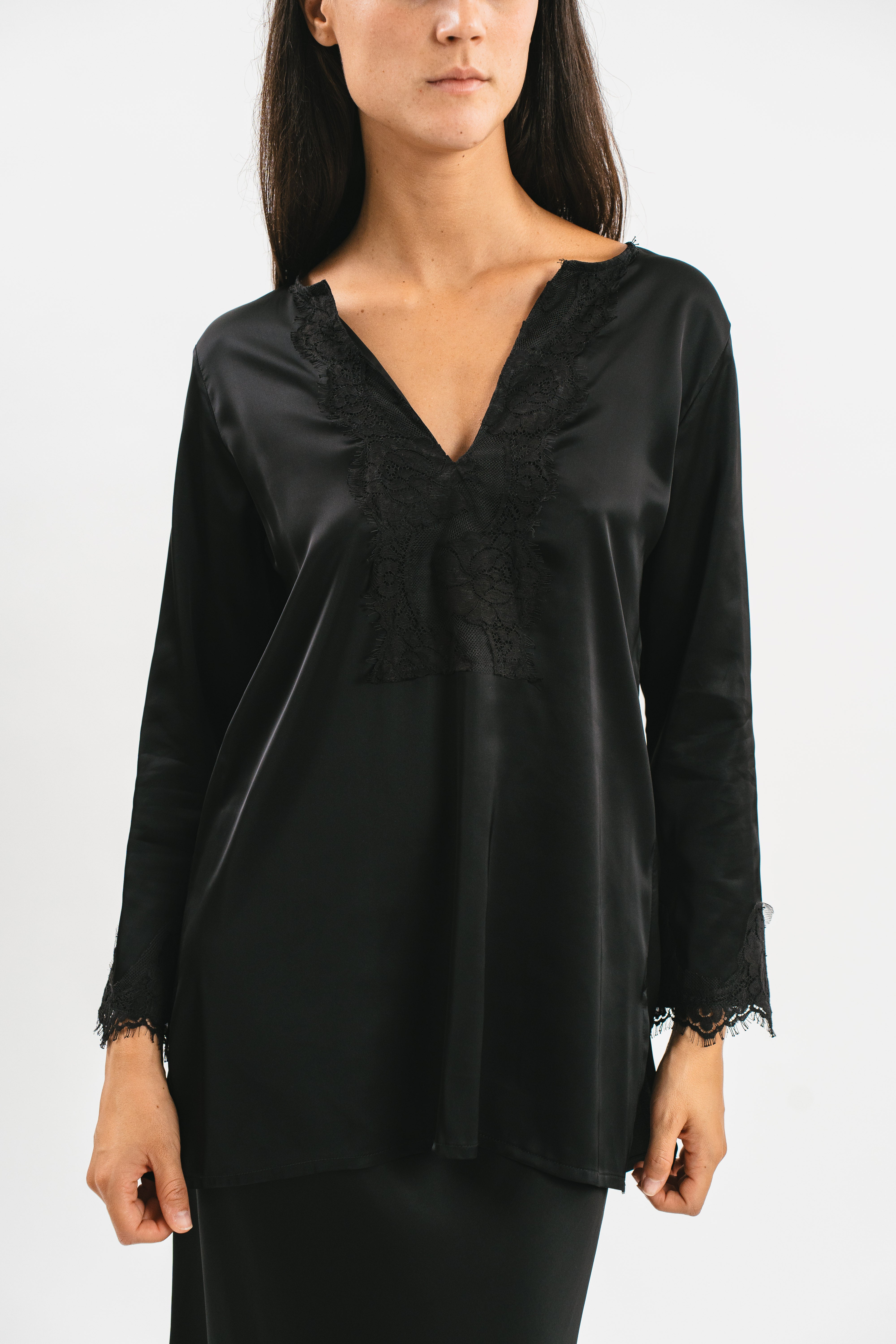 Modella indossa camicia in viscosa satin elasticizzata con rifiniture in pregiato pizzo francese manica ¾ e spacchetti laterali. Dettaglio