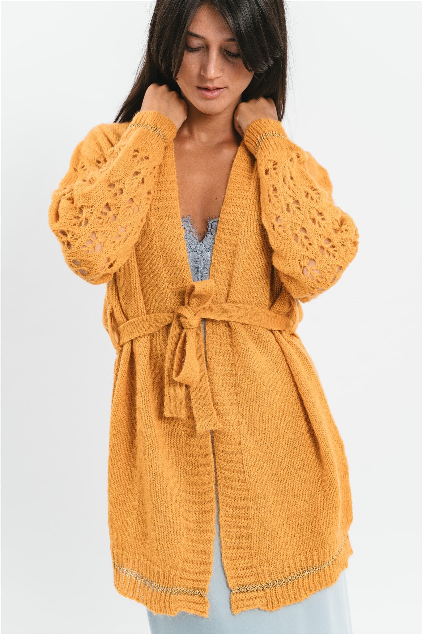 Modella indossa cardigan giallo ocra corto con maniche traforate. Dettaglio