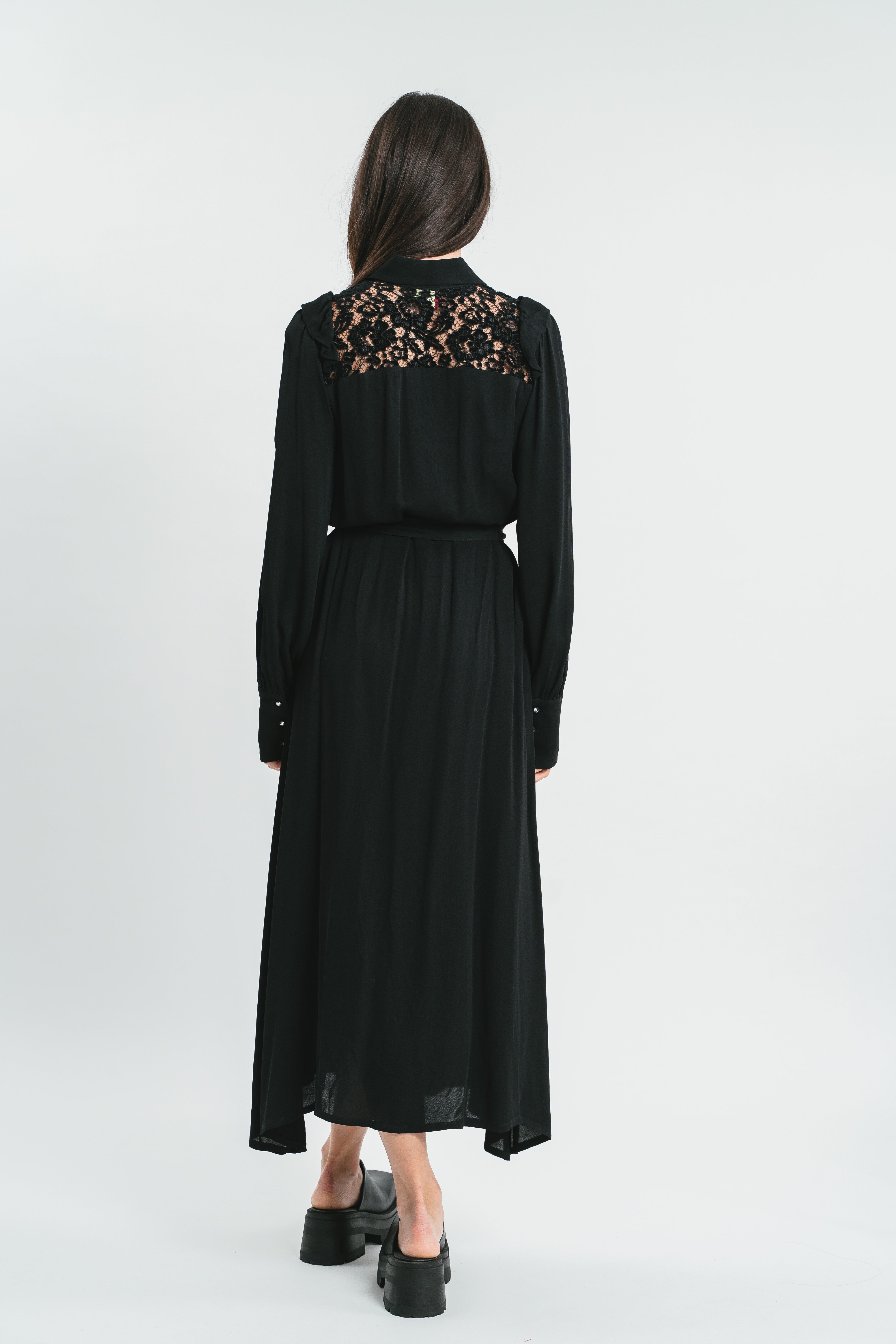 Modella indossa abito nero lungo con plastron di pizzo. Posteriore