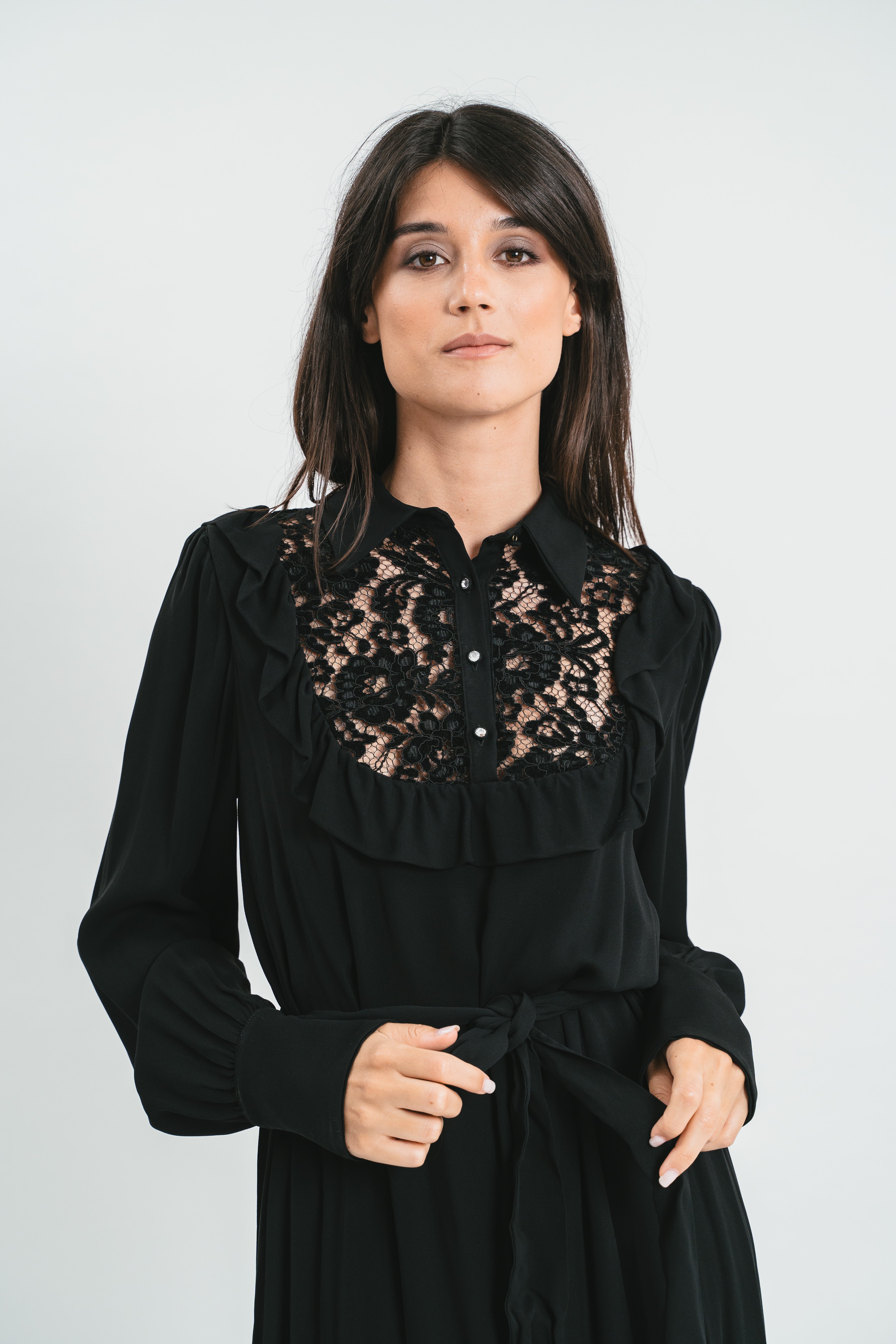 Modella indossa abito nero lungo con plastron di pizzo. Dettaglio