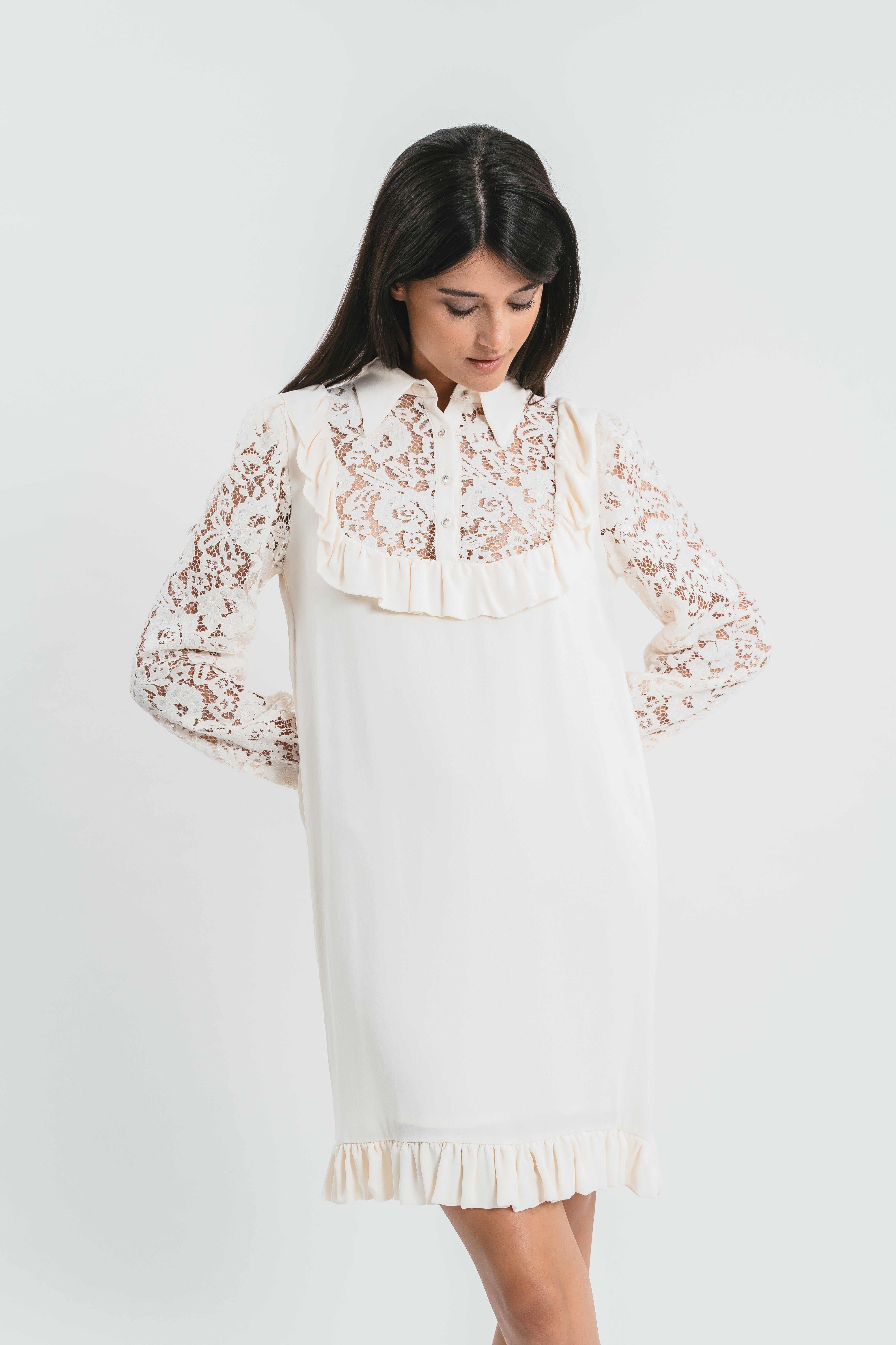 Modella indossa abito bianco corto con plastron di pizzo. Dettaglio