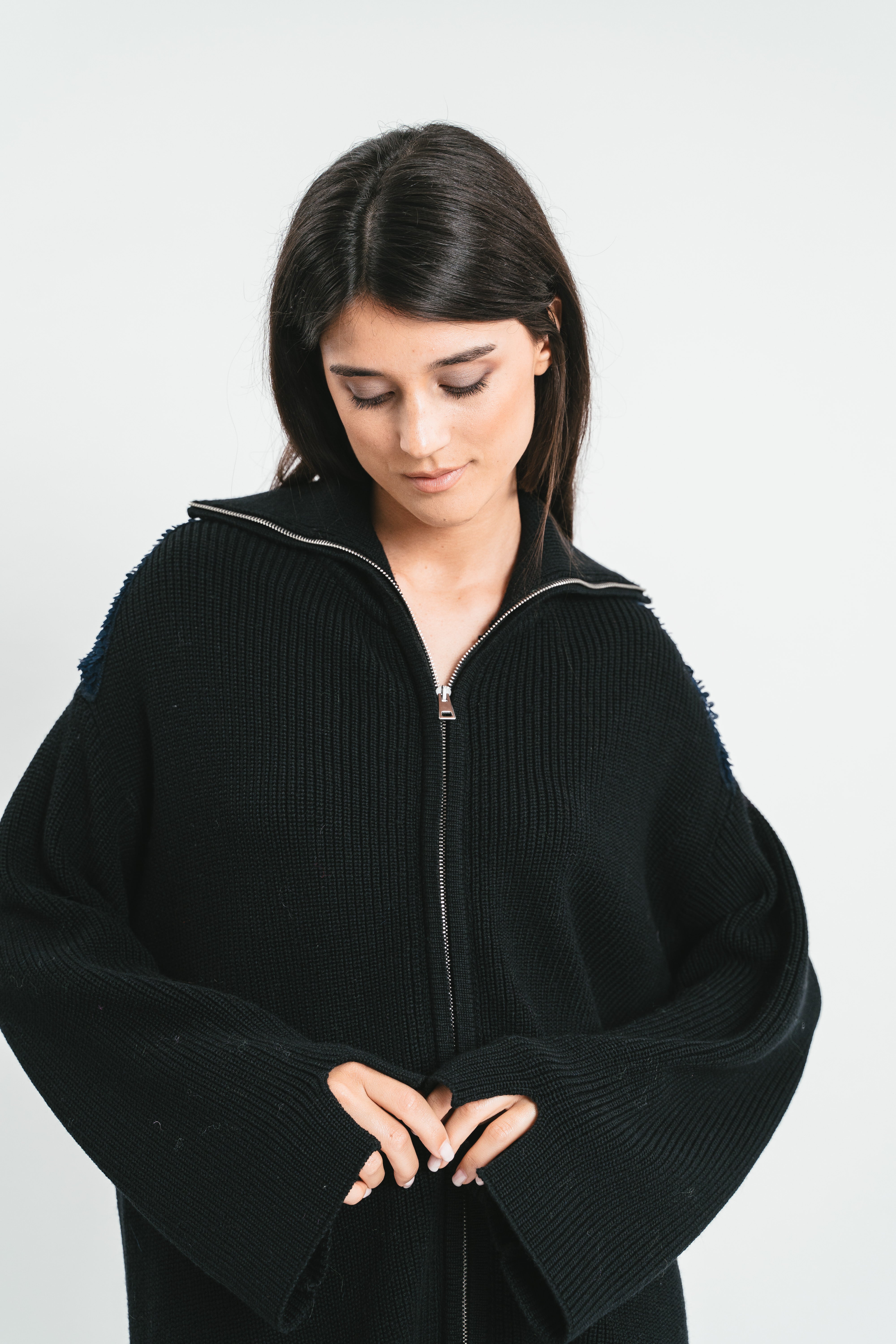 Modella indossa cardigan over nero con zip e colletto. Dettaglio