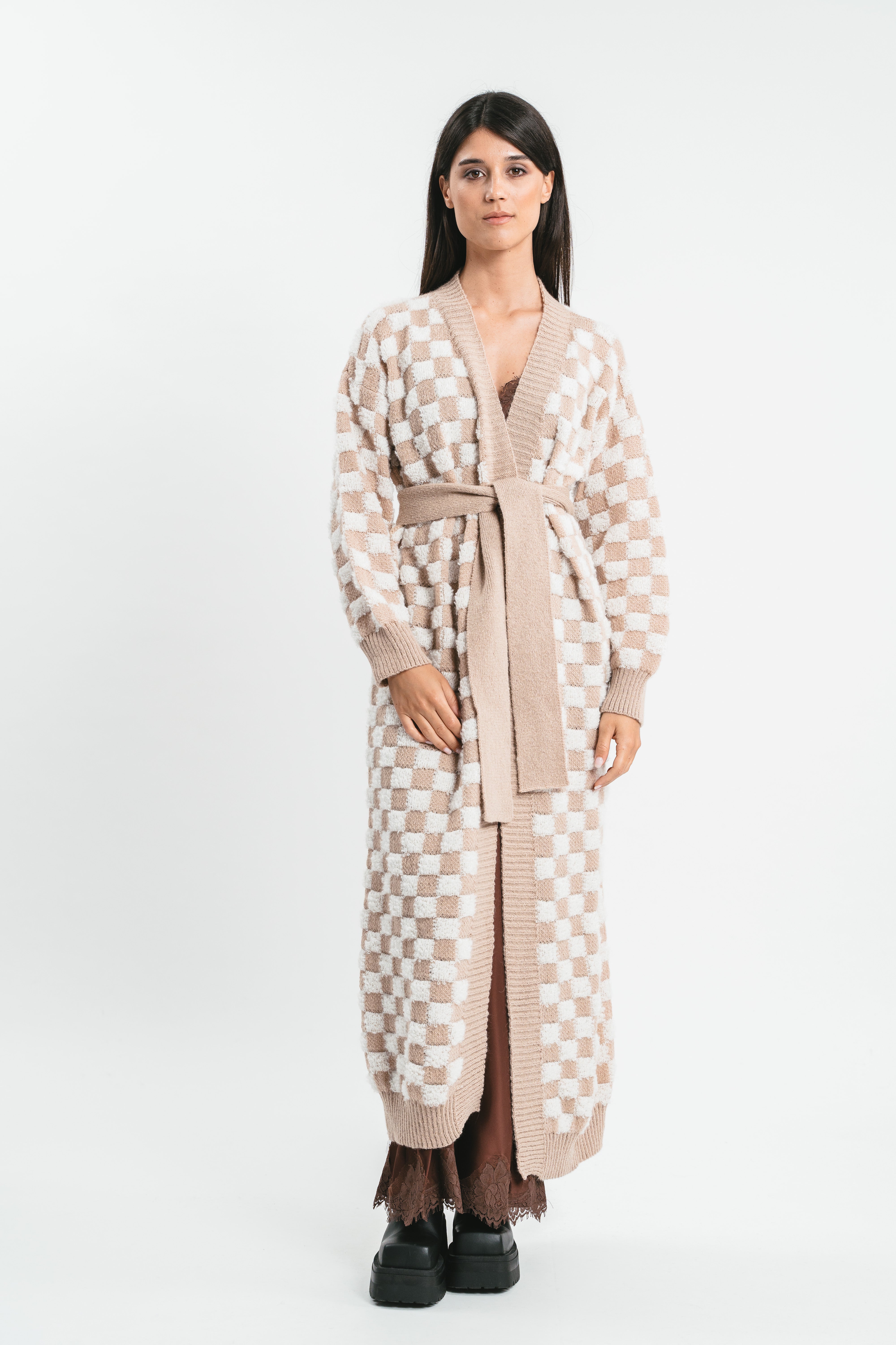 Modella indossa cappotto cardigan bianco e beige a quadri con cintura in coordinato. Frontale