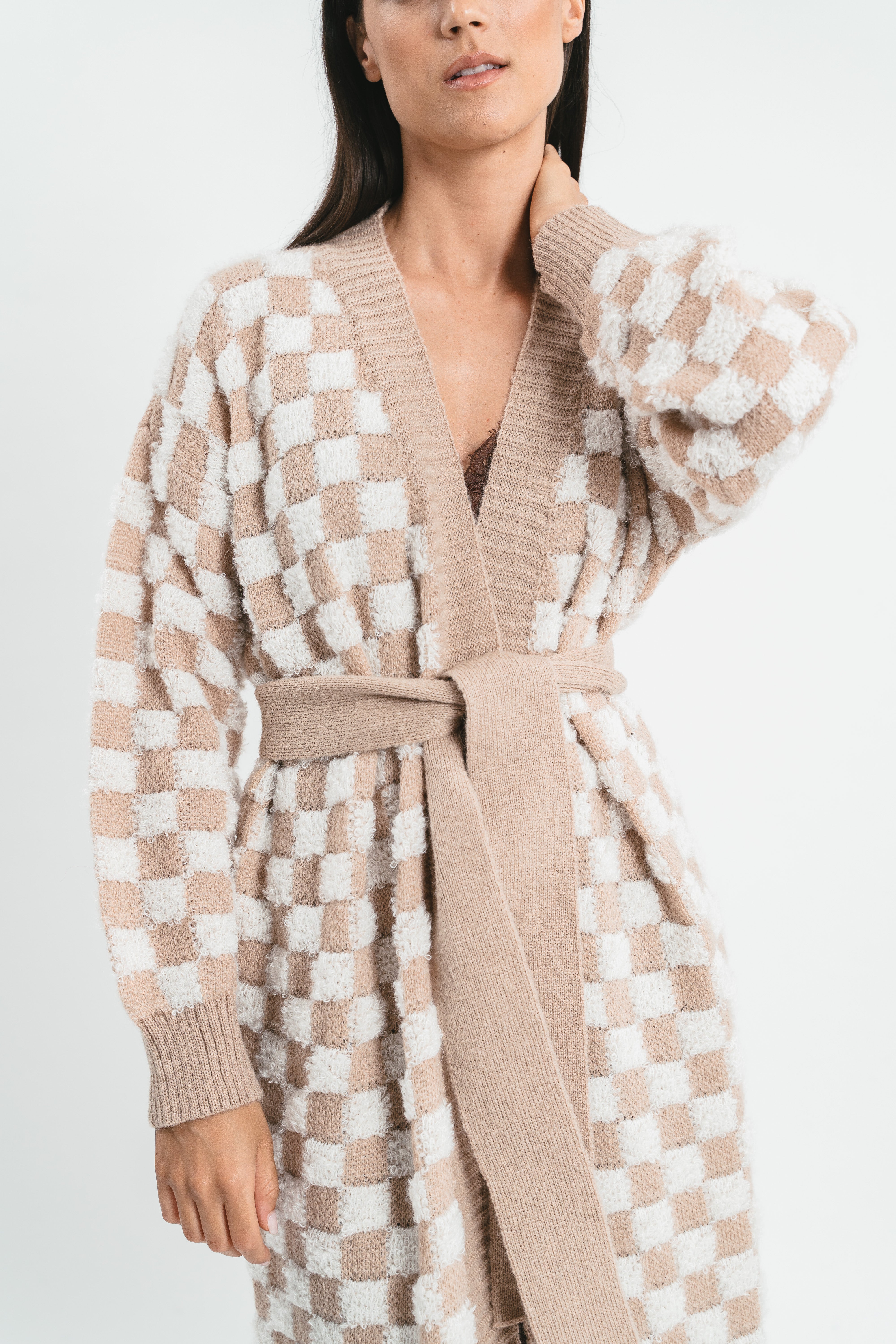 Modella indossa cappotto cardigan bianco e beige a quadri con cintura in coordinato. Dettaglio