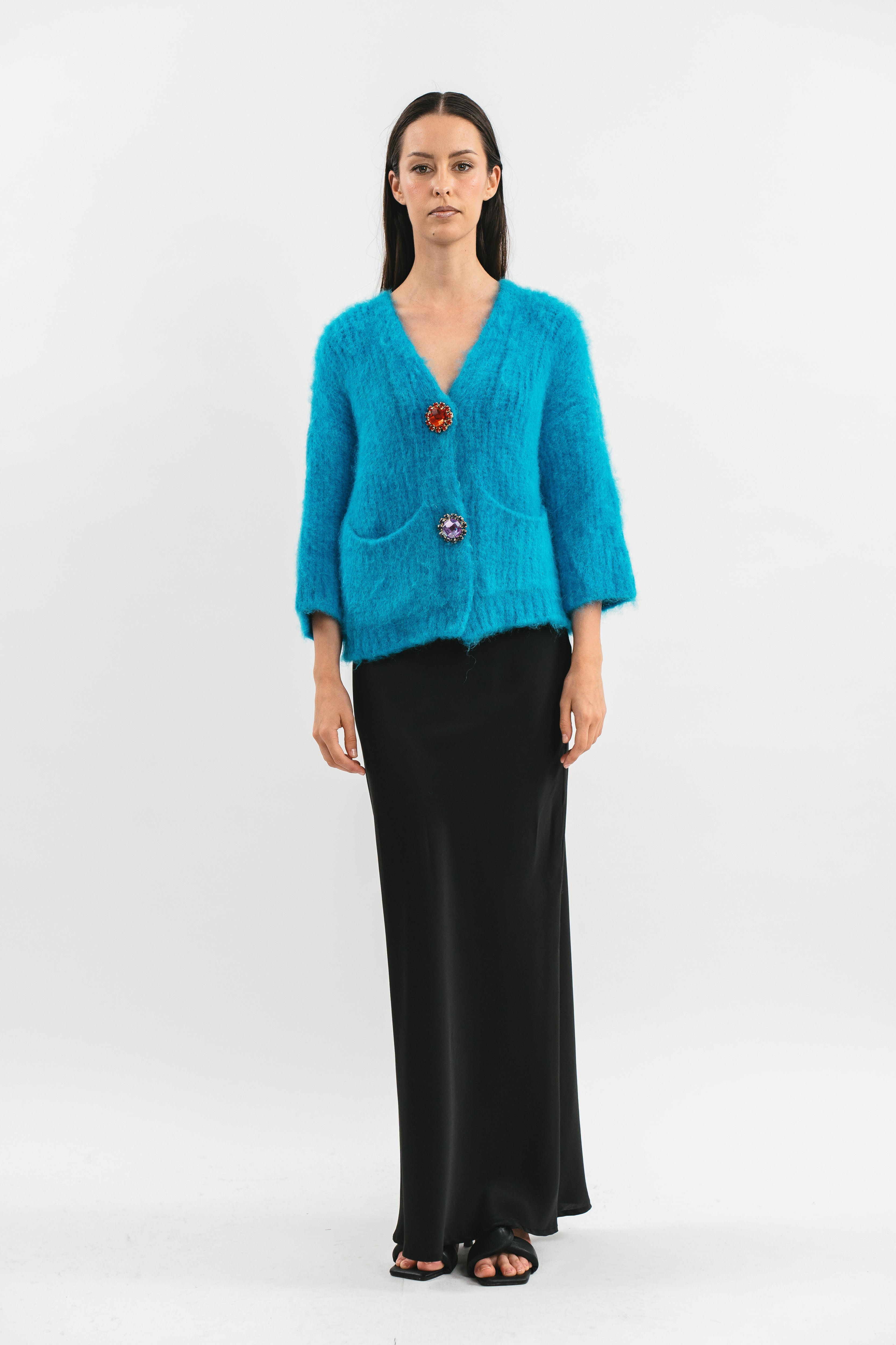Modella indossa cardigan over turchese in Alpaca con tasche e spille gioiello. Frontale