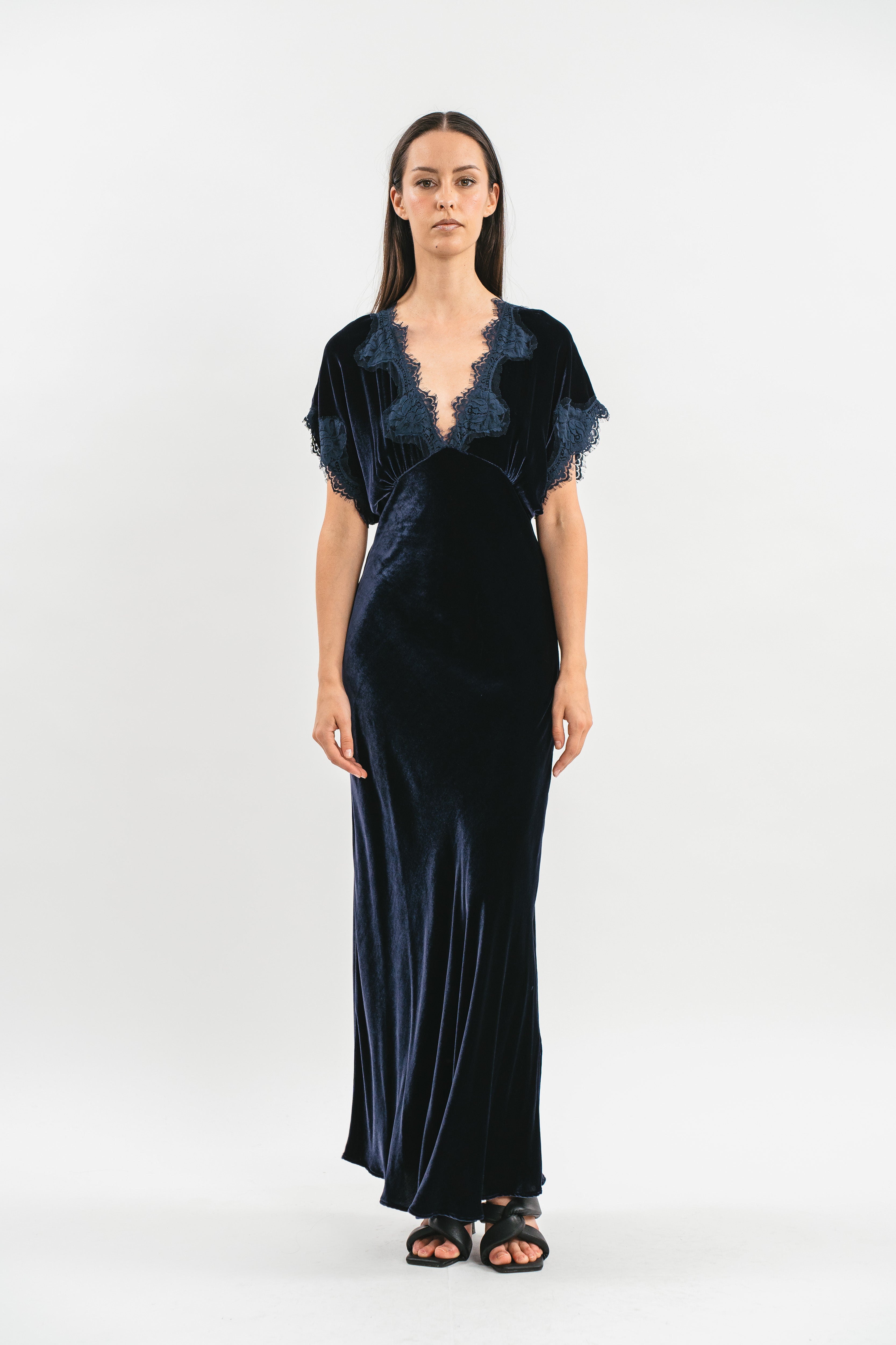 Modella indossa abito blu navy in velluto con mezze maniche e pizzo. Frontale