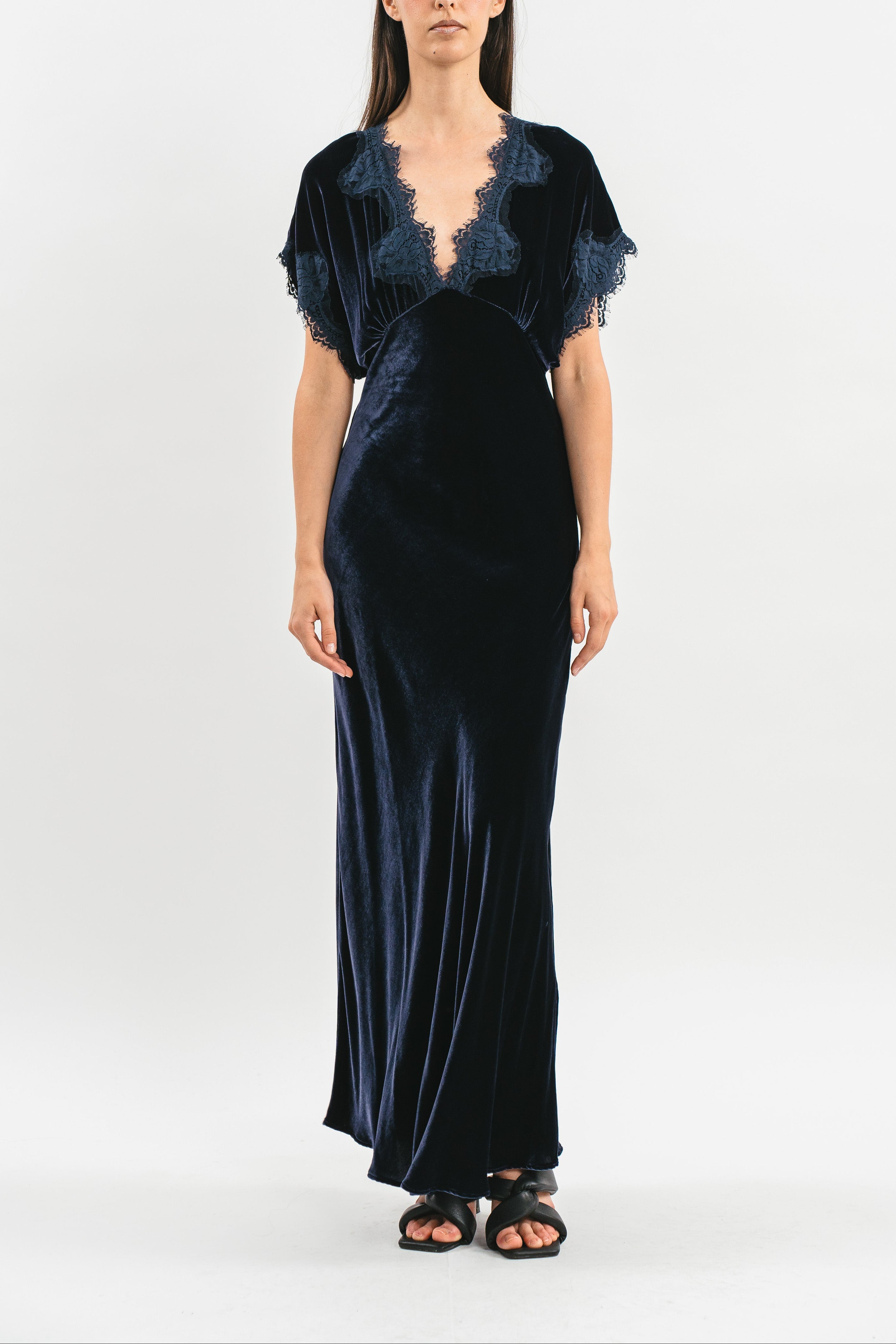 Modella indossa abito blu navy in velluto con mezze maniche e pizzo. Frontale