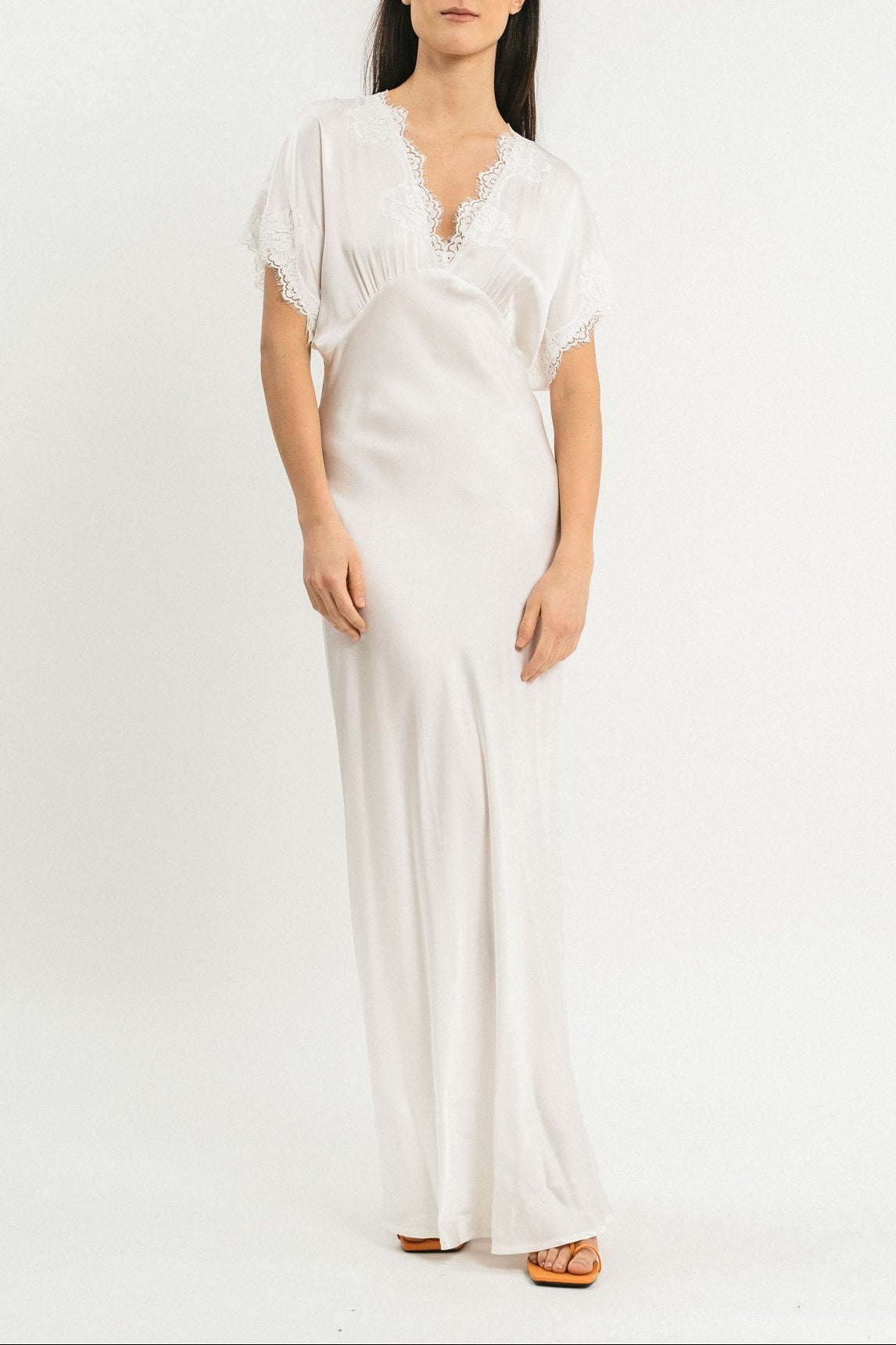 Modella indossa abito bianco lungo in viscosa elasticizzata con rifiniture in pizzo francese. Fronte