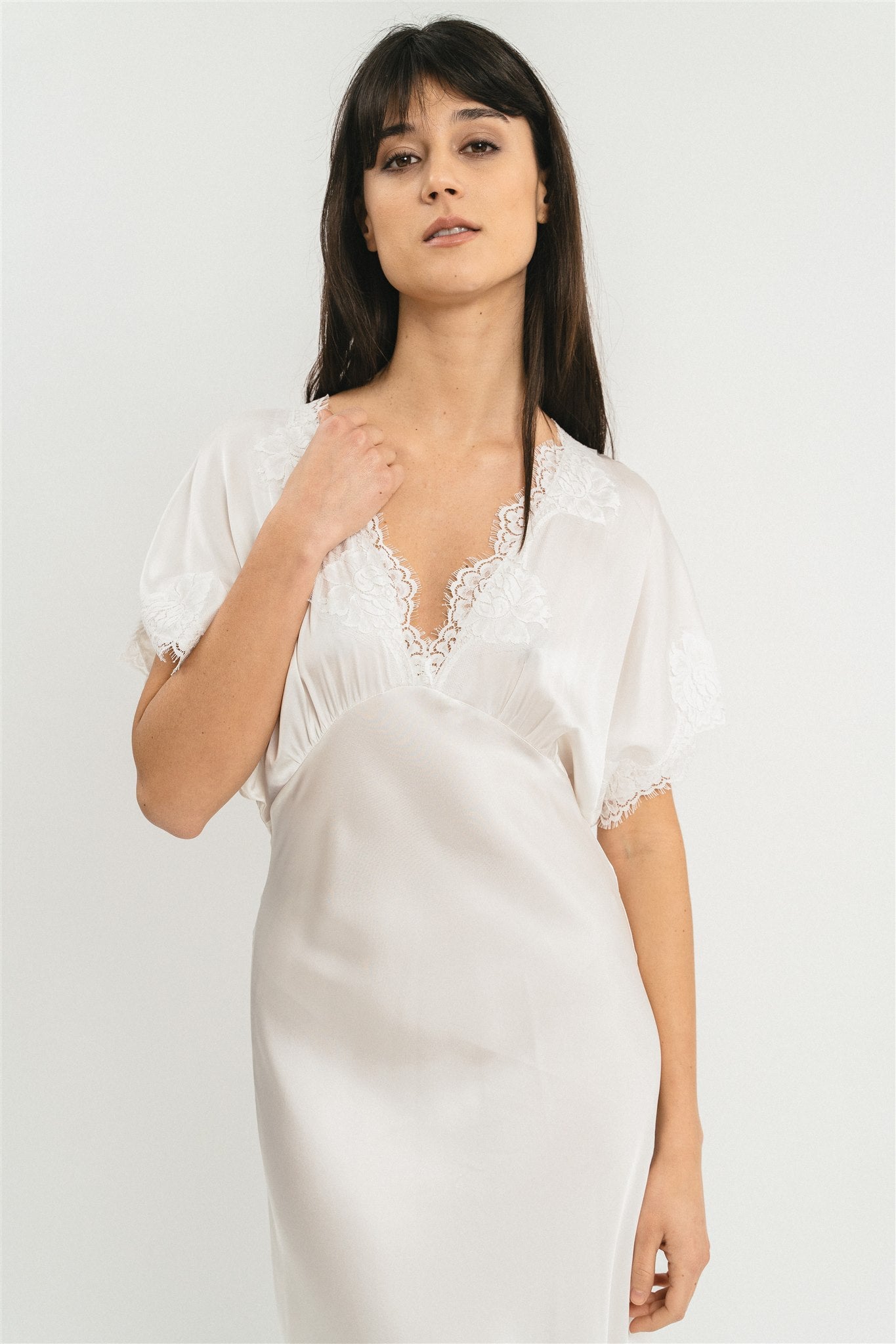Modella indossa abito bianco lungo in viscosa elasticizzata con rifiniture in pizzo francese. Dettaglio