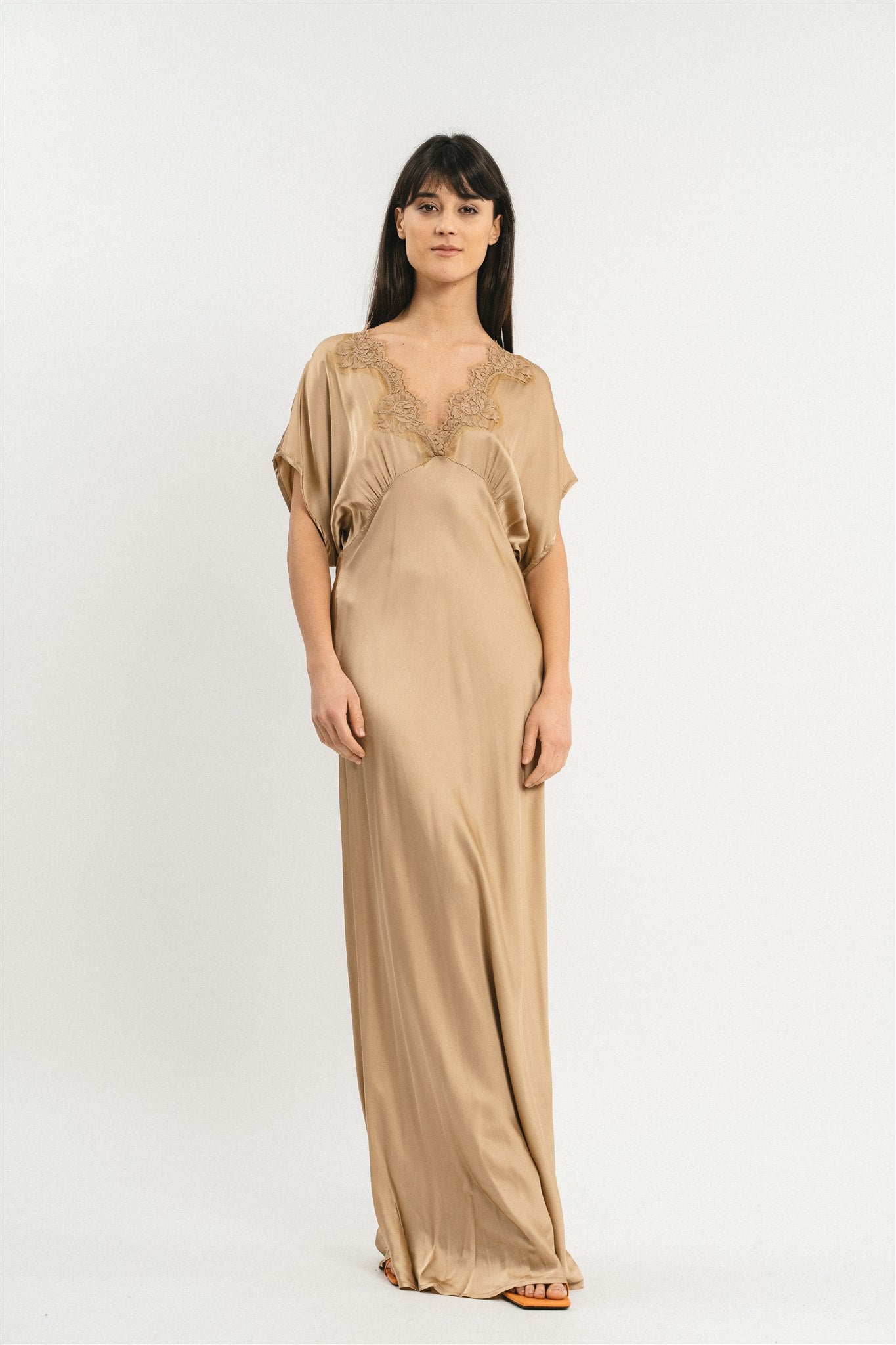 Modella indossa abito di colore cammello lungo in viscosa elasticizzata con rifiniture in pizzo francese. Fronte