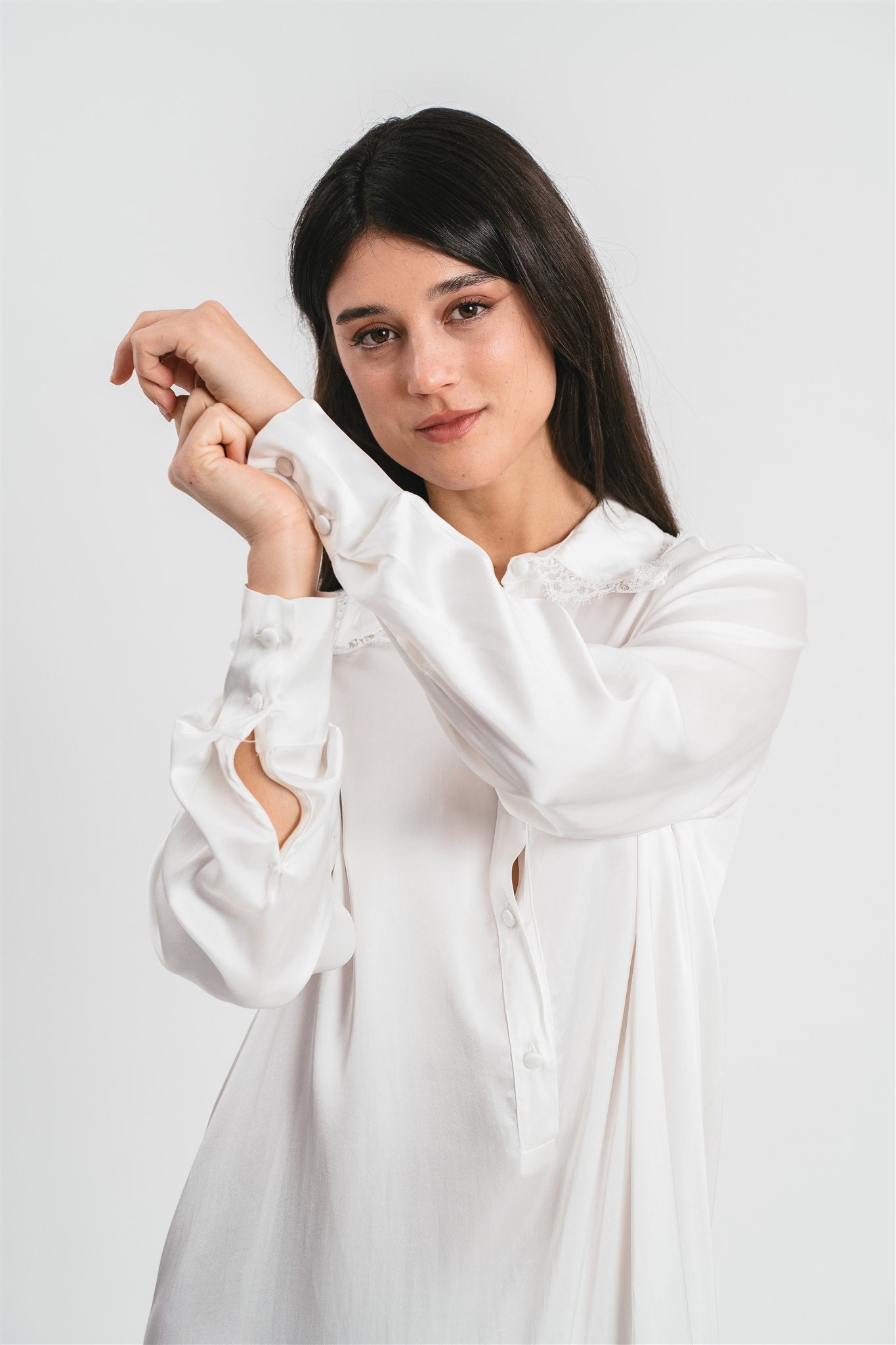 Modella indossa chemisier bianco con maniche lunghe, spacchi sul fondo e dettagli in pizzo. Dettaglio