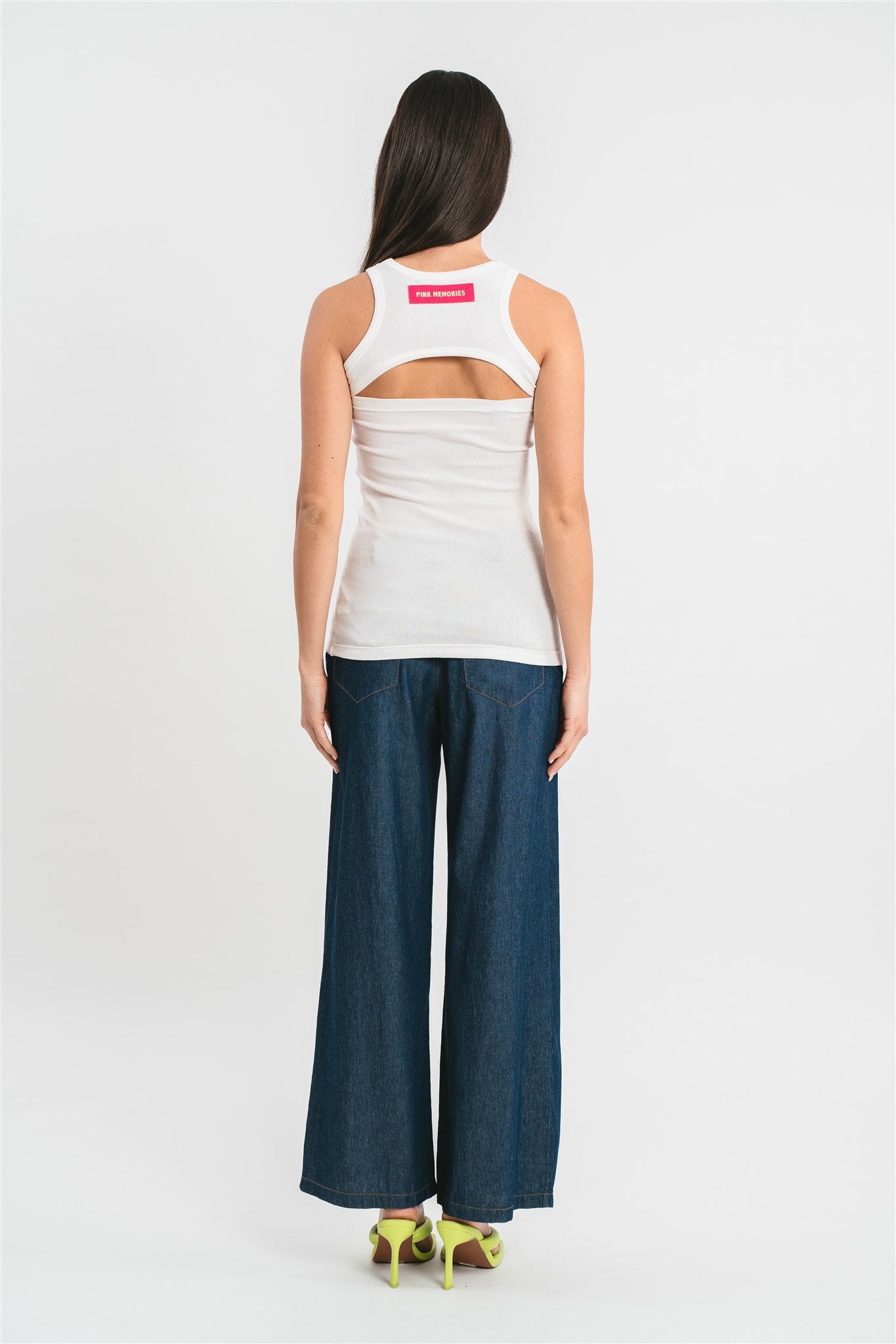 Modella indossa canotta bianca a costine con cut-out e dettagli in pizzo francese. Posteriore
