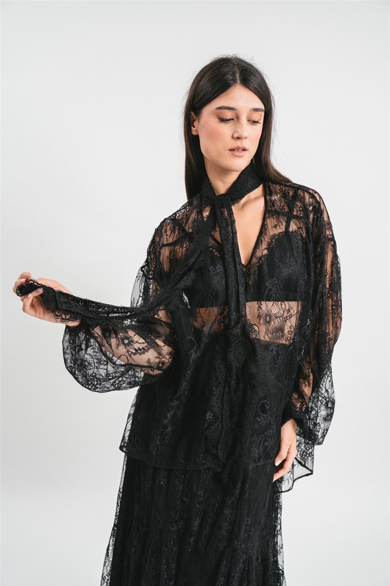 Modella indossa camicia in pizzo con scollo a V fiocco frontale e maniche ampie. Dettaglio