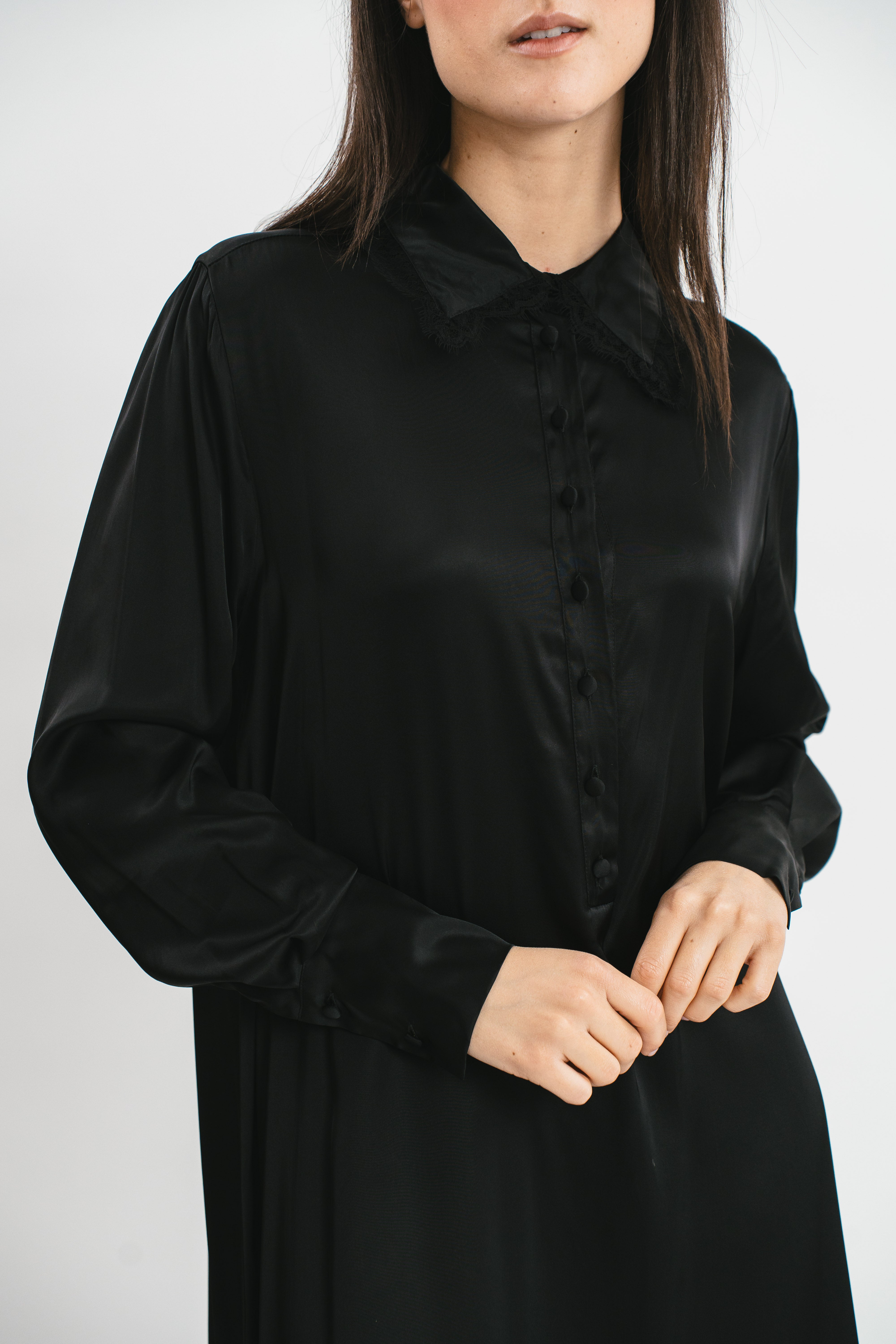 Modella indossa chemisier nero con maniche lunghe, spacchi sul fondo e dettagli in pizzo. Dettaglio