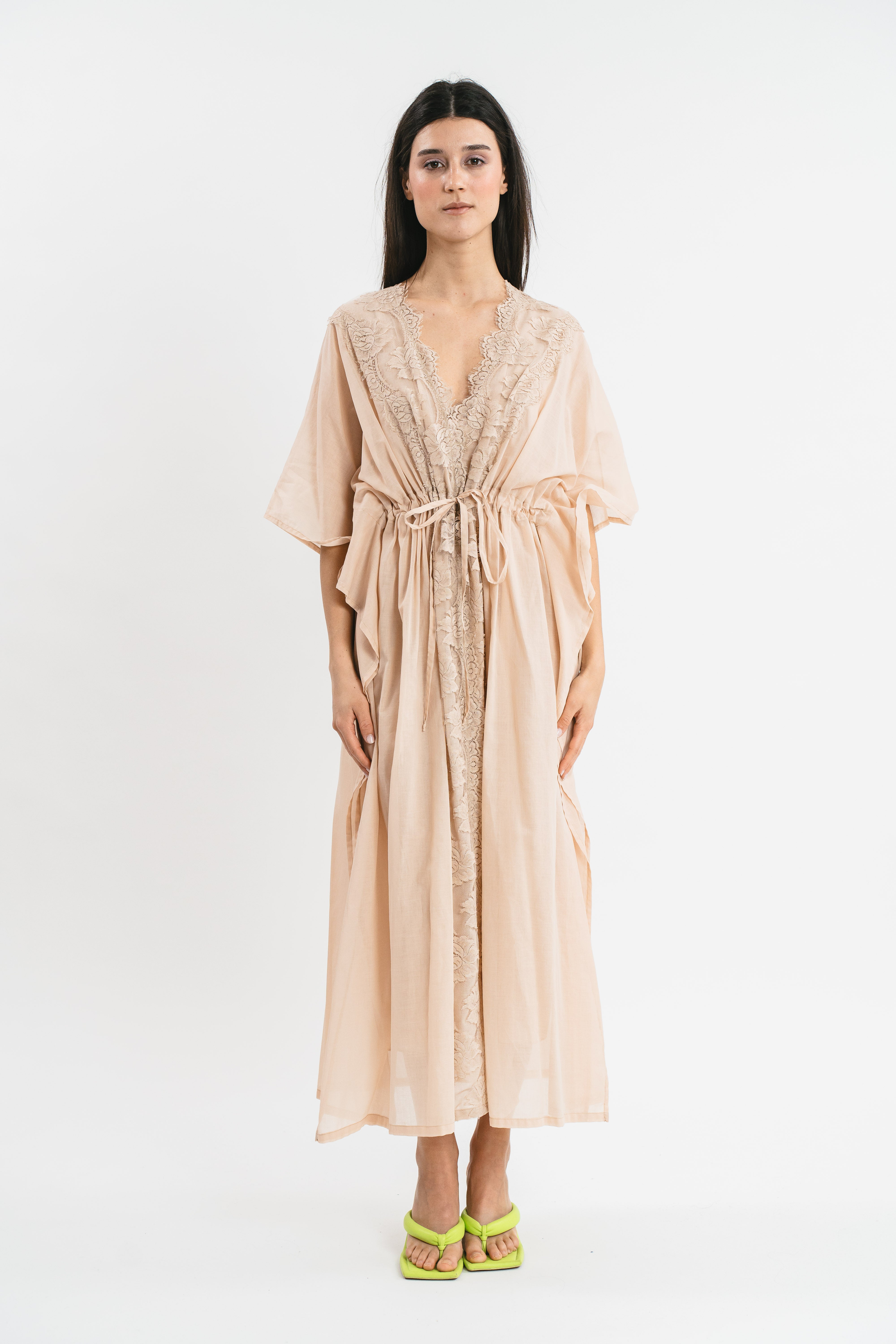 Modella indossa caftano beige con dettagli in pizzo. Frontale