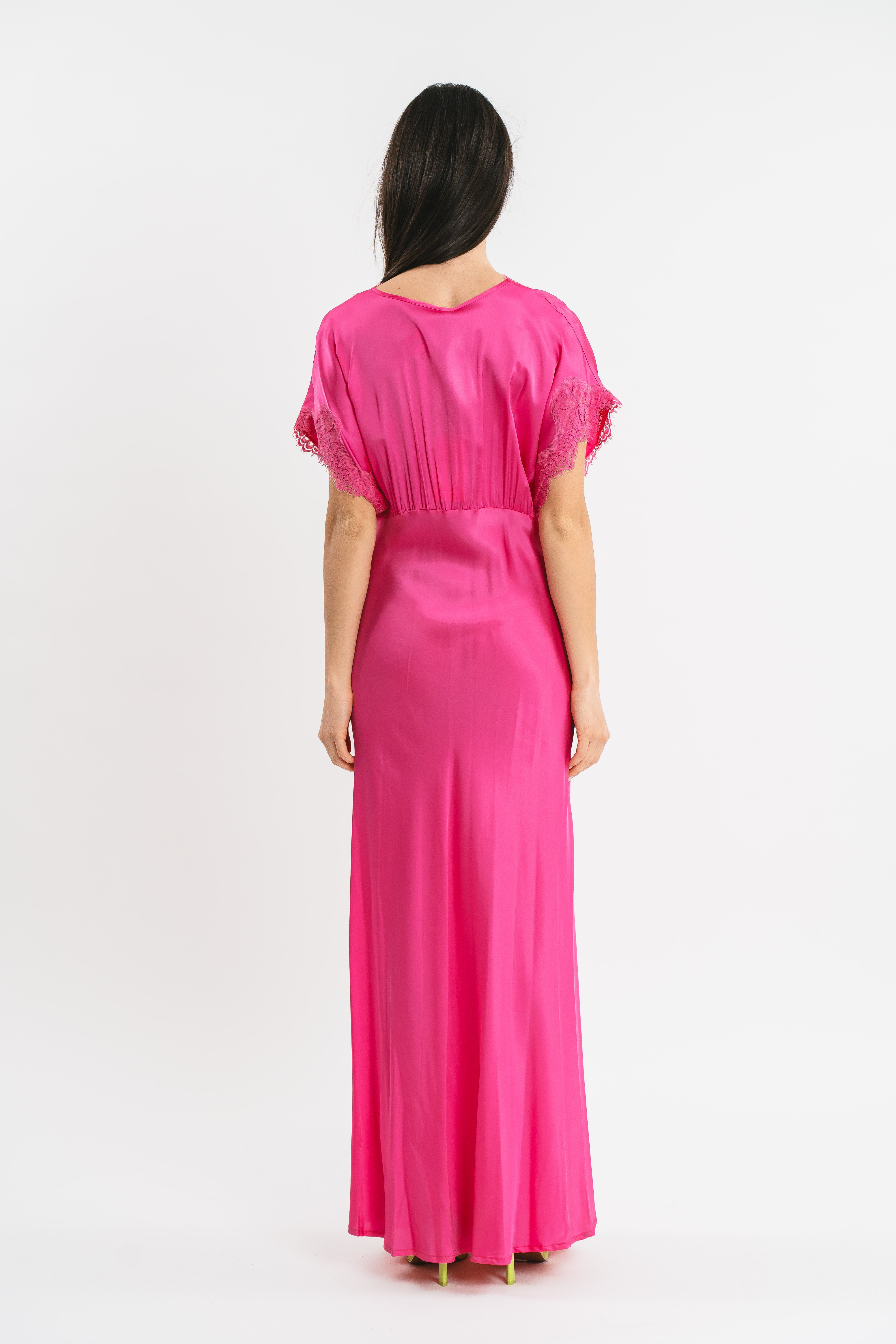 Modella indossa abito fuxia lungo in viscosa elasticizzata con rifiniture in pizzo francese. Posteriore