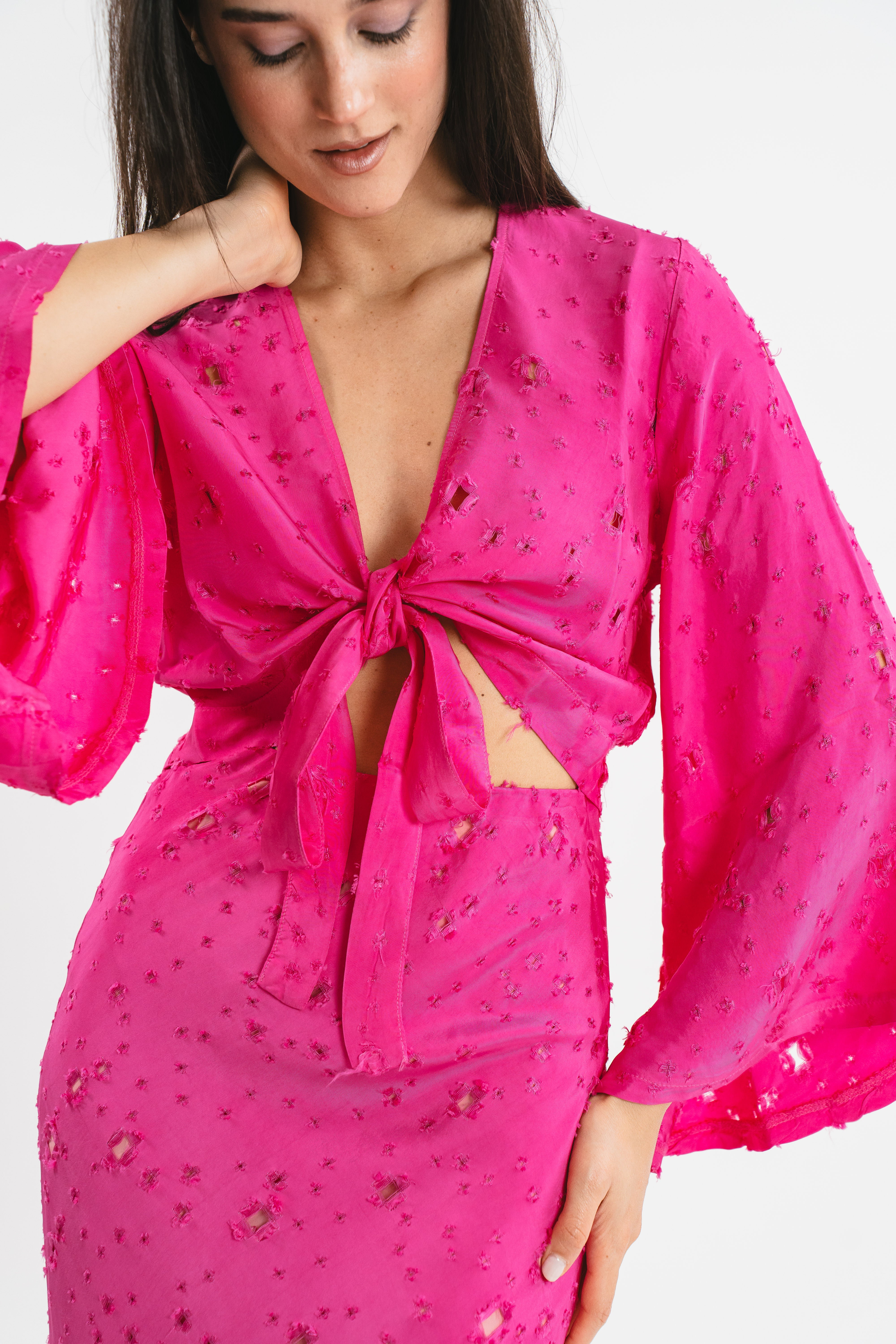 Crop top fucsia traforato con fiocco frontale e maniche ampie. Dettaglio