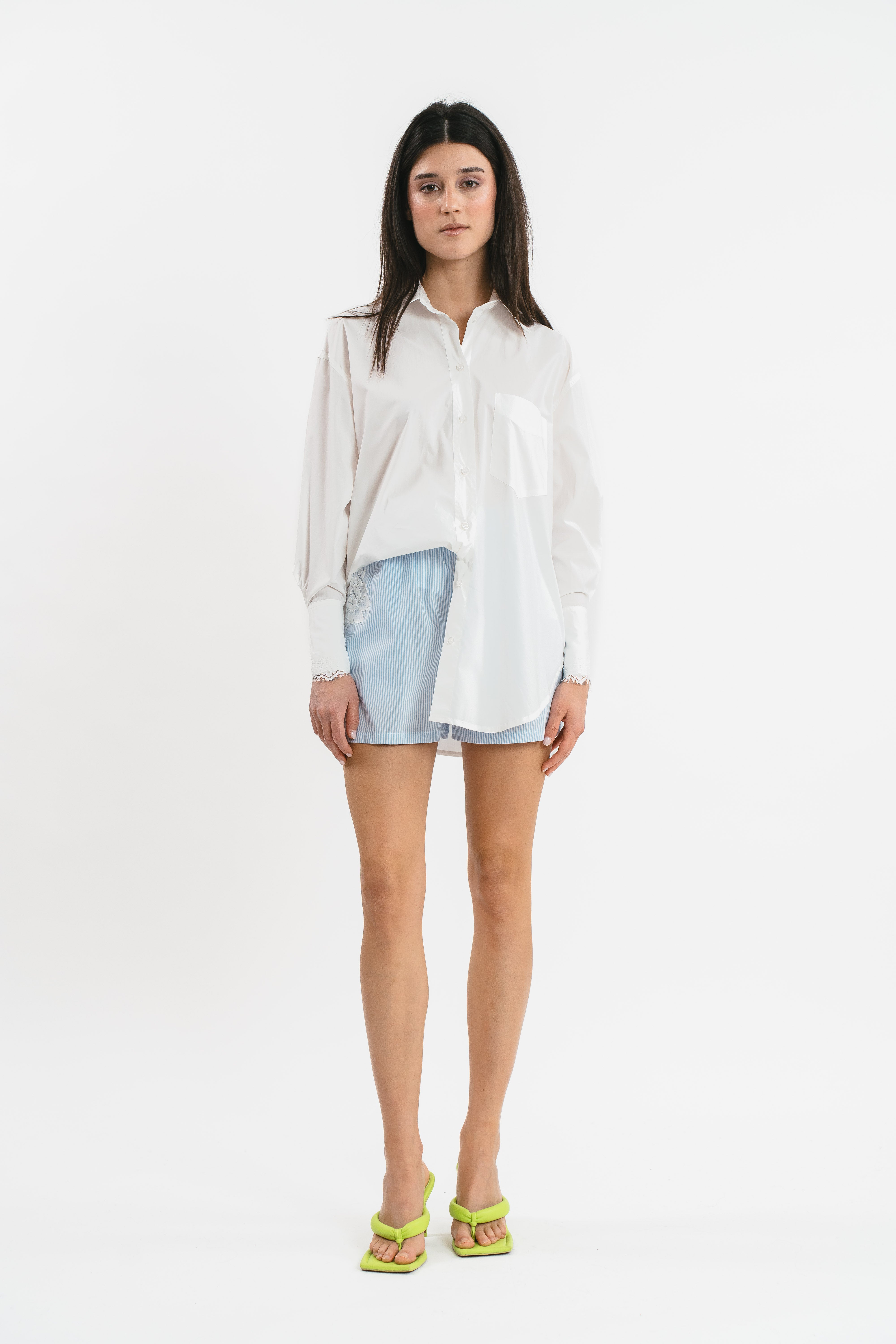 Modella indossa camicia bianca a righe con dettagli in pizzo.