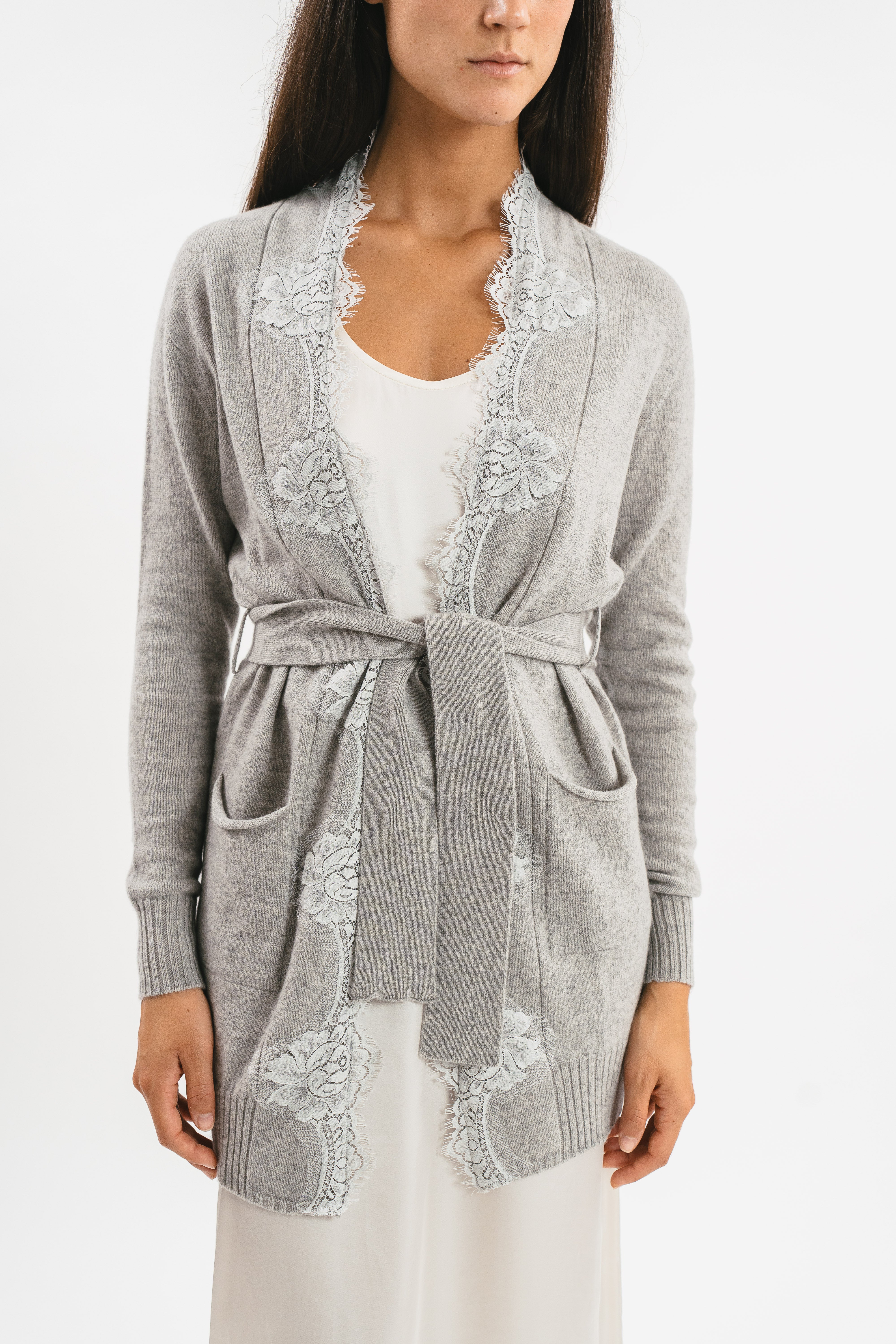 Modella indossa cardigan grigio cachemire con cintura e pizzo. Dettaglio