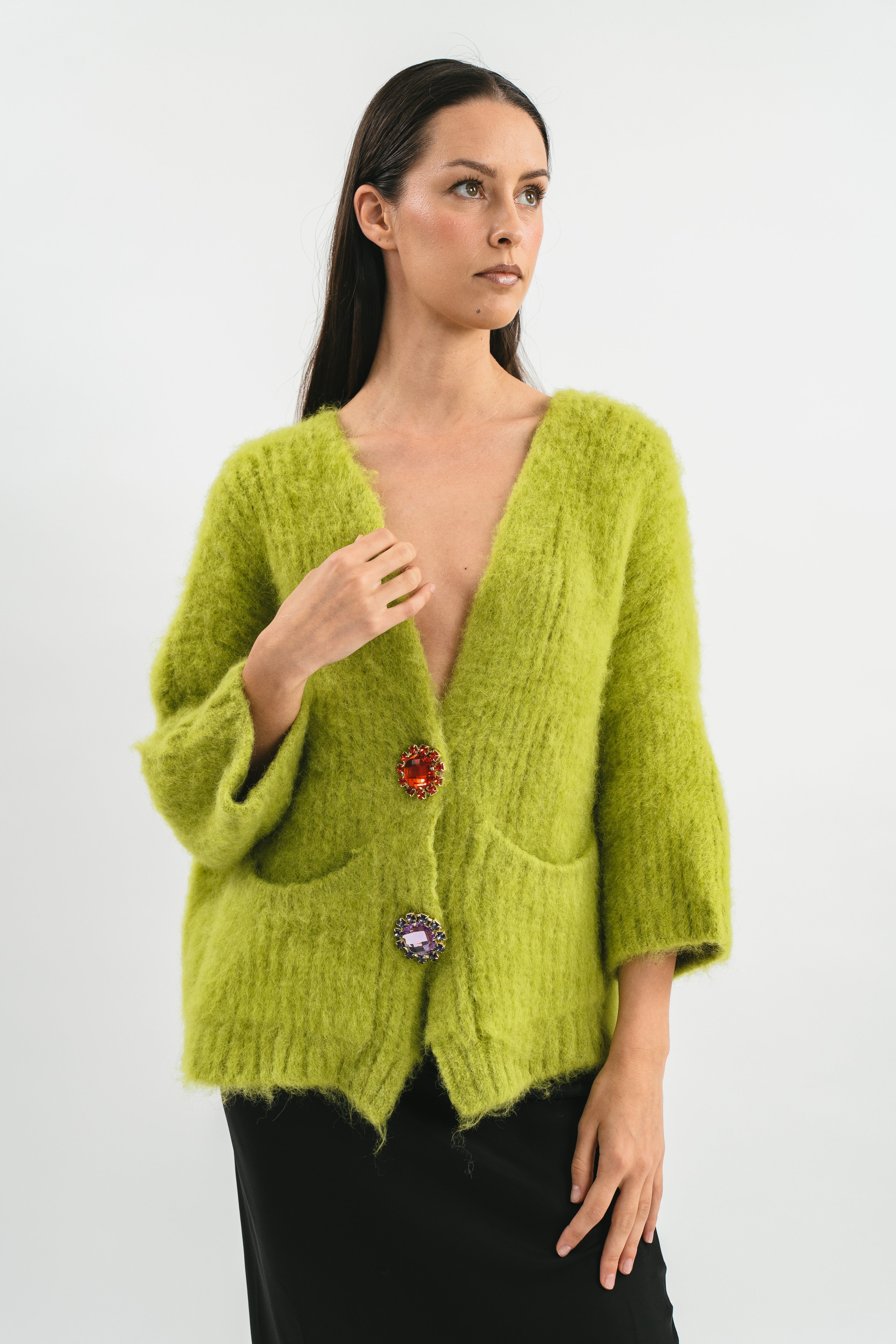 Modella indossa cardigan over verde in Alpaca con tasche e spille gioiello. Dettaglio