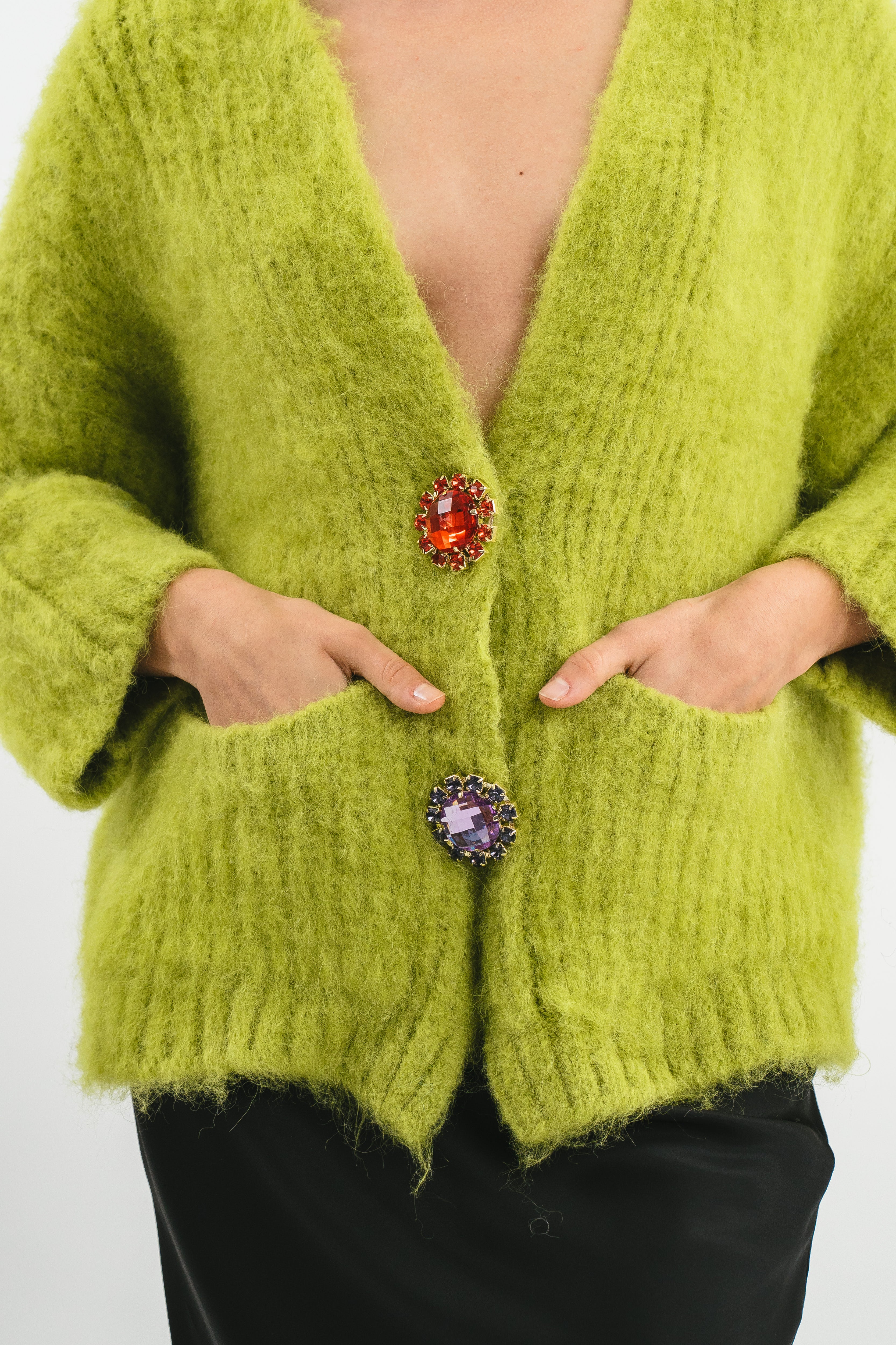 Modella indossa cardigan over verde in Alpaca con tasche e spille gioiello. Dettaglio