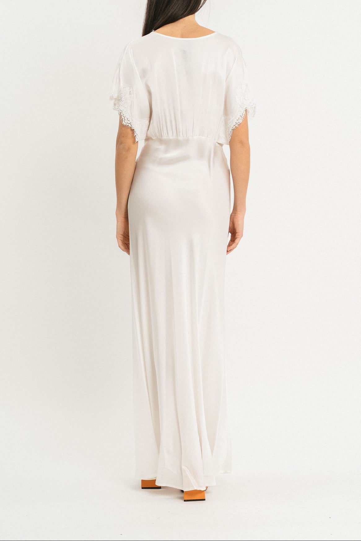 Modella indossa abito bianco lungo in viscosa elasticizzata con rifiniture in pizzo francese. Retro