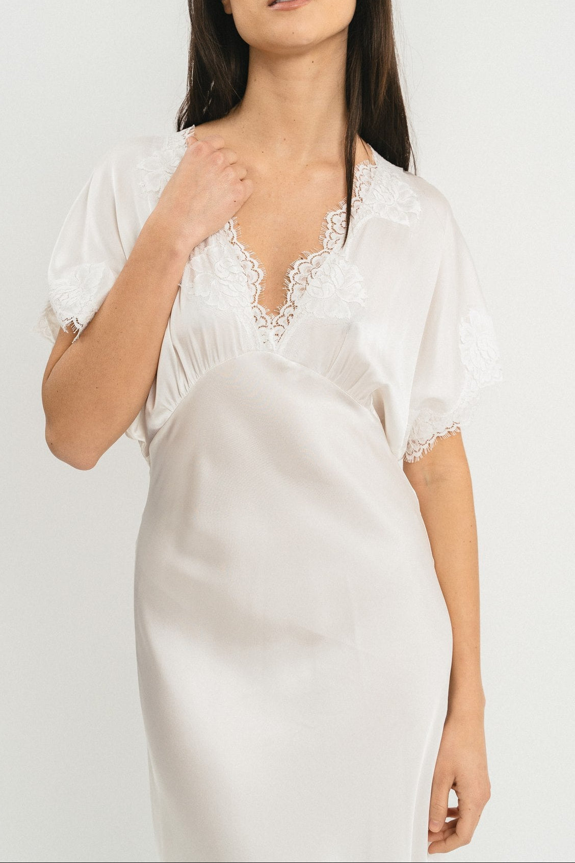 Modella indossa abito bianco lungo in viscosa elasticizzata con rifiniture in pizzo francese. Dettaglio
