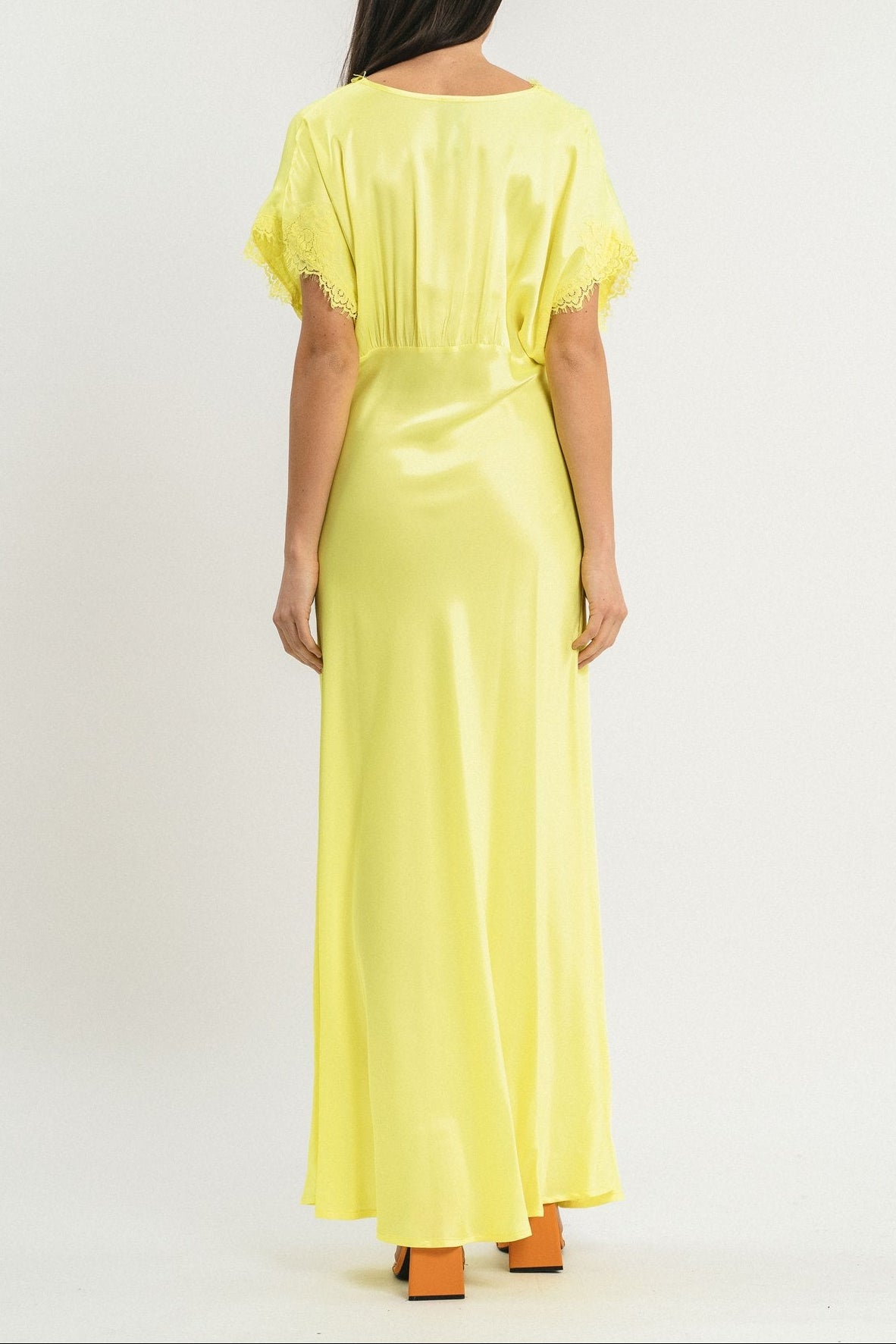 Modella indossa abito giallo lungo in viscosa elasticizzata con rifiniture in pizzo francese. Posteriore