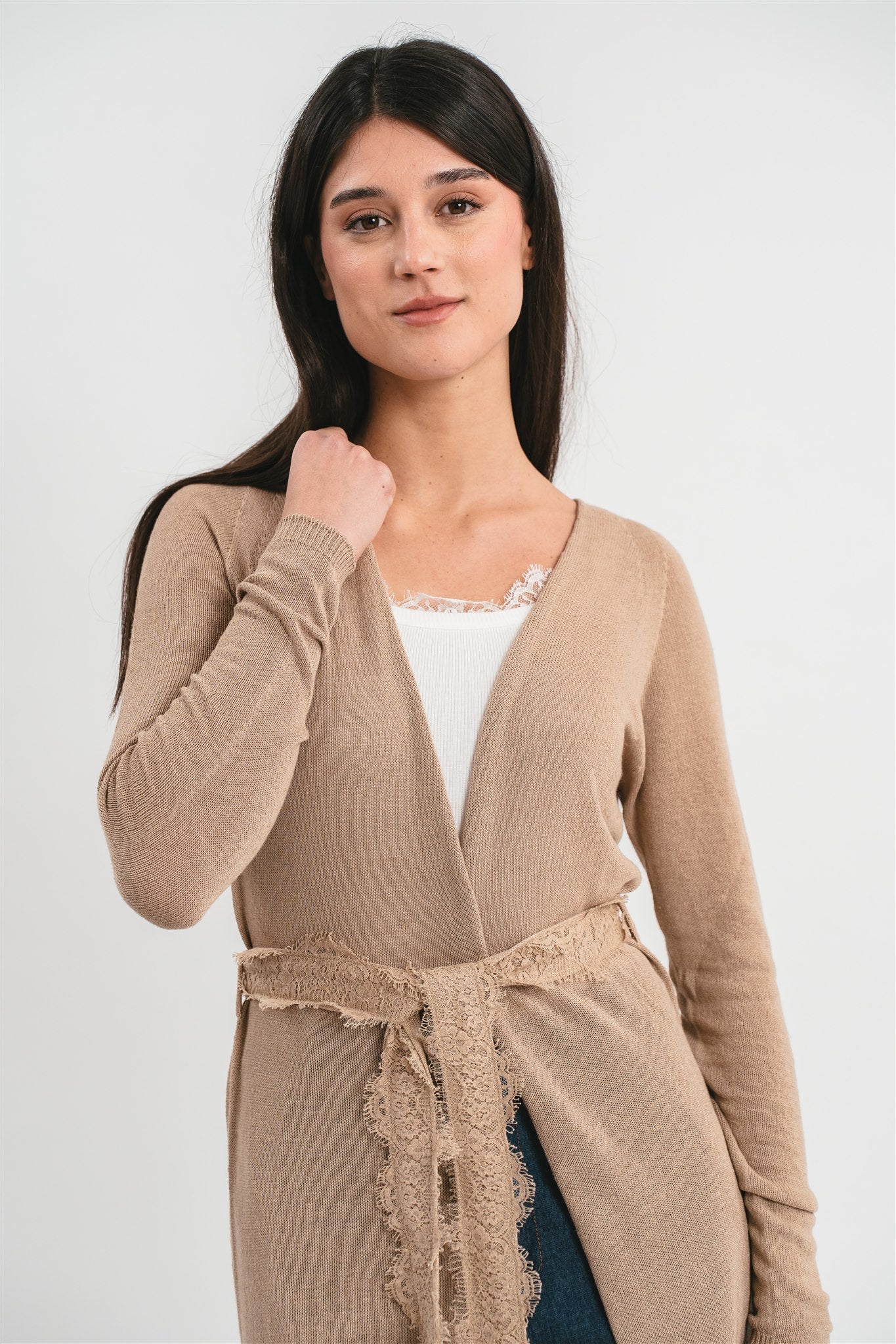 Modella indossa cardigan color cammello con cintura e dettagli in pizzo francese. Dettaglio